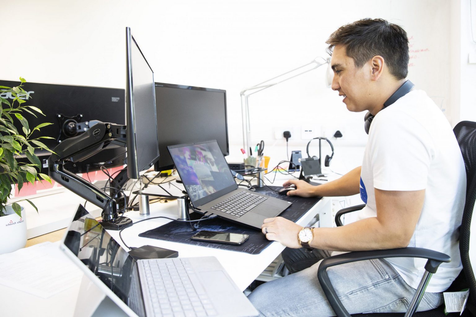 man in ventura digital office sat at computer and laptop with plant
